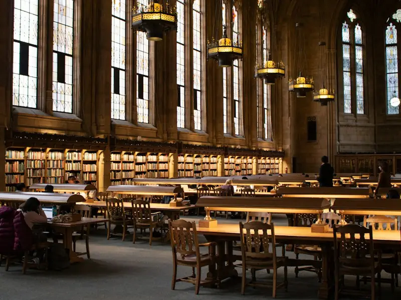 Students studying at long tables in a grand old library